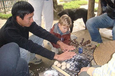 Lan and Benji warming their hands by the grill