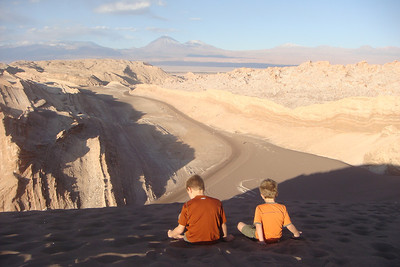 the boys playing in the sand on the top of the dune