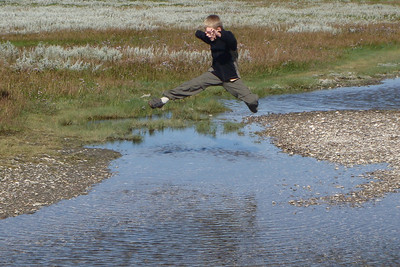 leaping an inlet on a pebbly beach